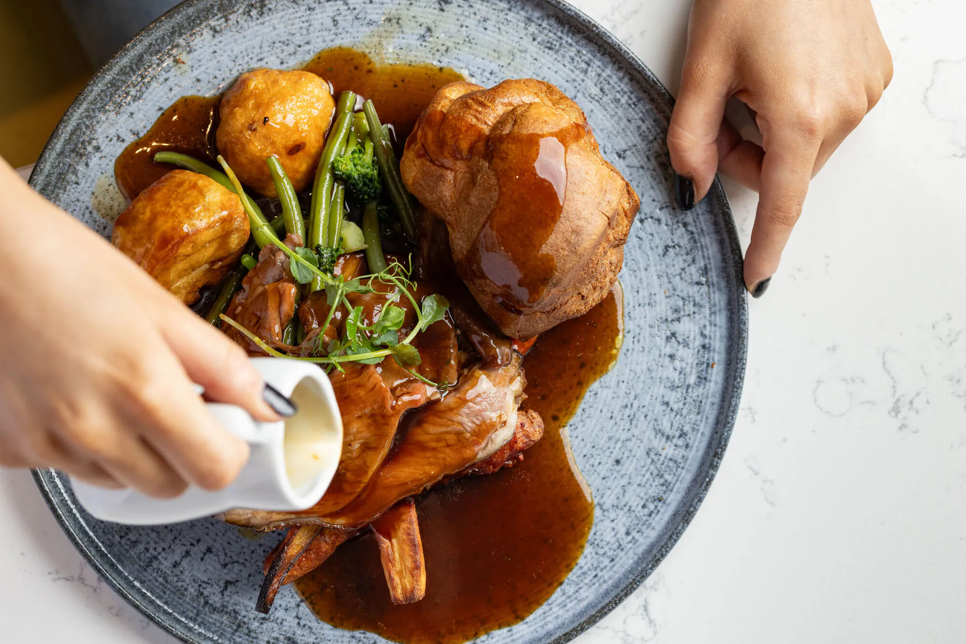Pouring gravy over a Sunday roast at Banana Wharf
